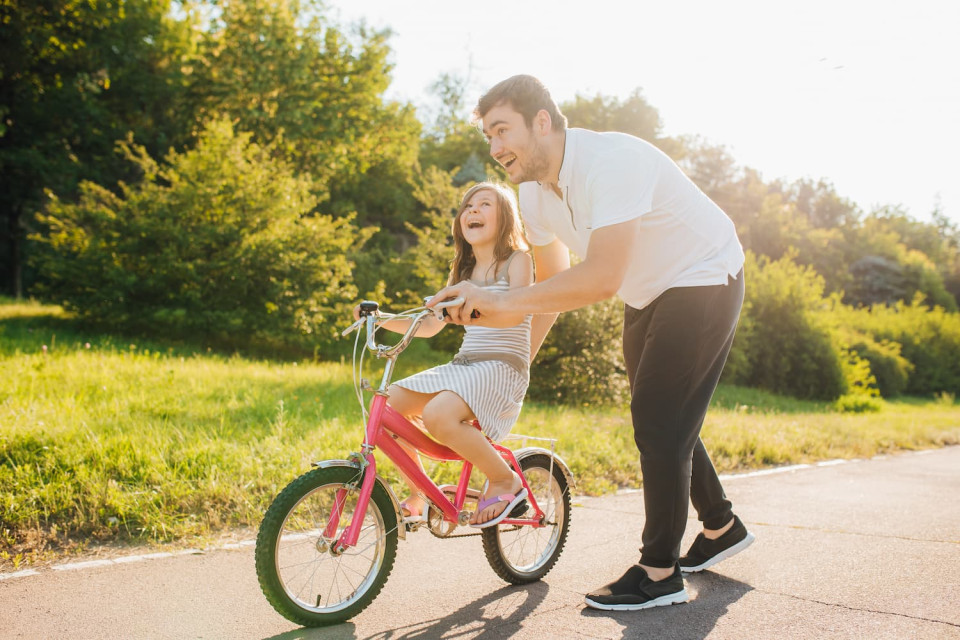 Father teaching his daughter how to ride a bicycle